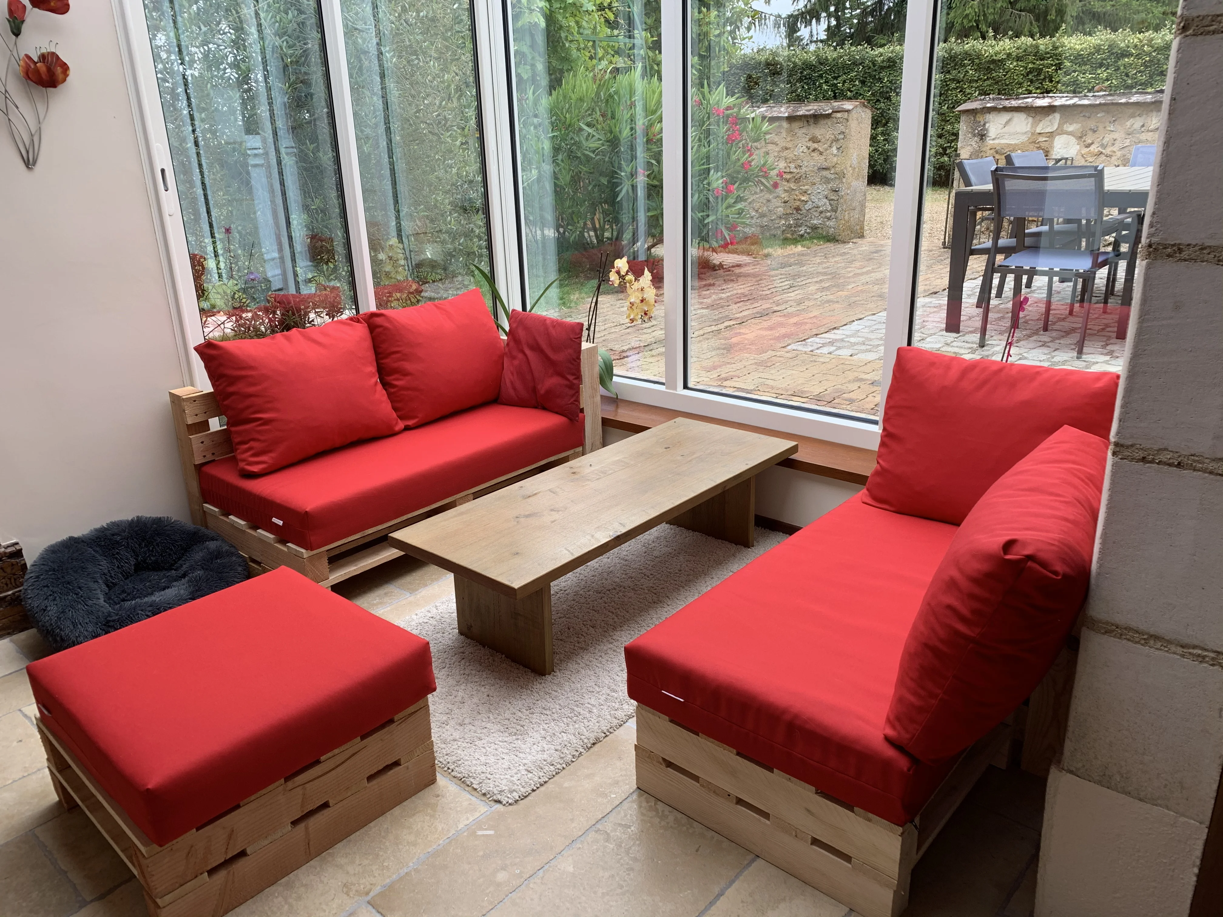 Salon rouge Modul’Pop dans une véranda ouverte sur le jardin